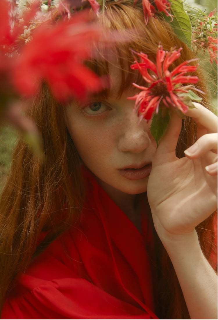 엔폴드의 빨간 원피스를 입고 붉은 꽃을 손에 쥐고 카메라를 응시하고 있는 붉은 머리 외국 여성 모델